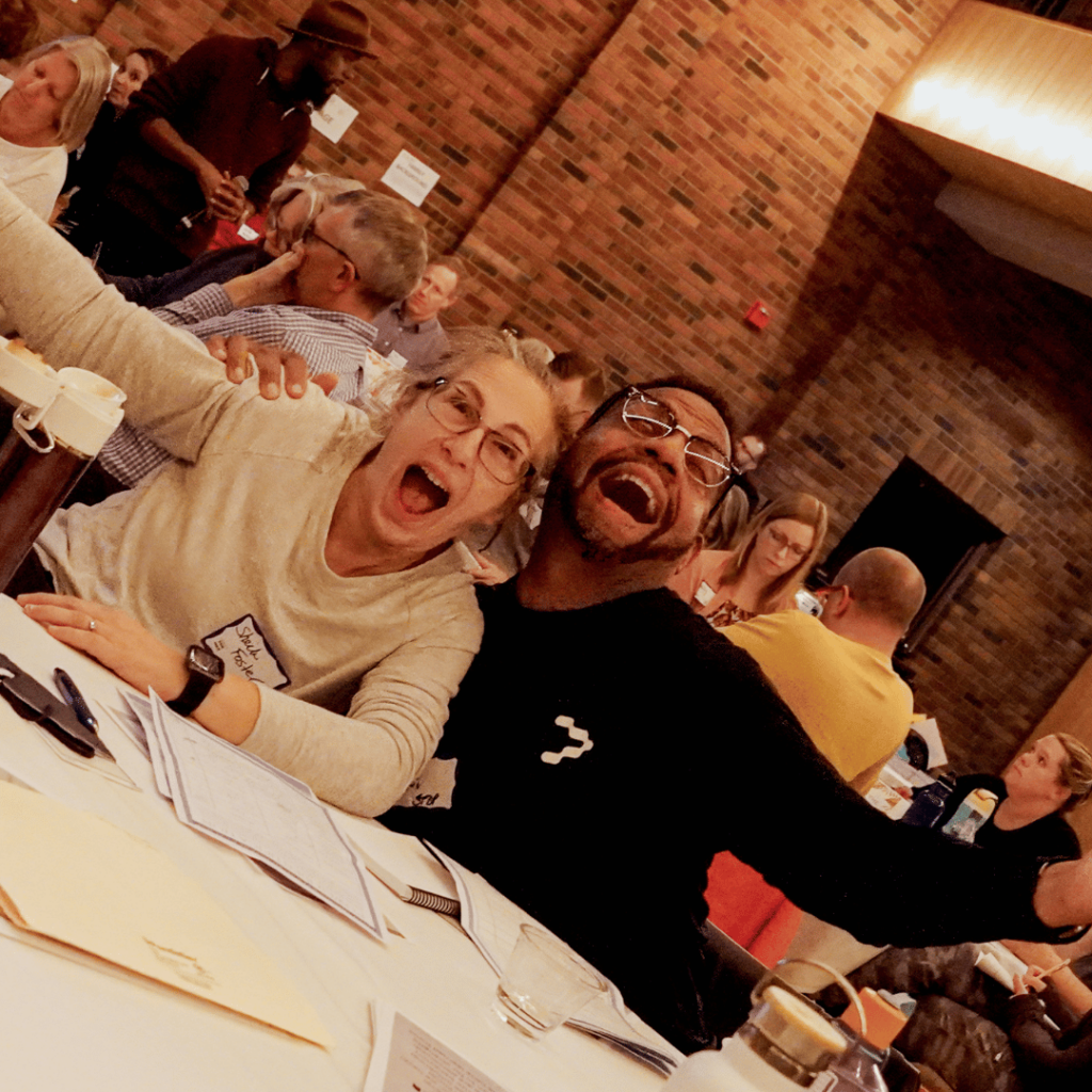 Two alum smiling while hugging at the table